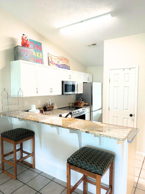 kitchen with kitchen peninsula, a kitchen breakfast bar, white cabinetry, and stainless steel appliances