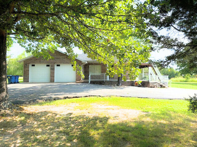 view of front of property featuring a garage, a front lawn, and covered porch