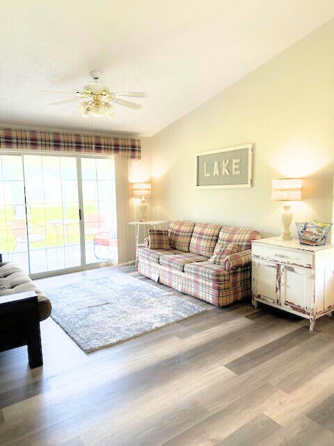 living room with ceiling fan, vaulted ceiling, and hardwood / wood-style floors