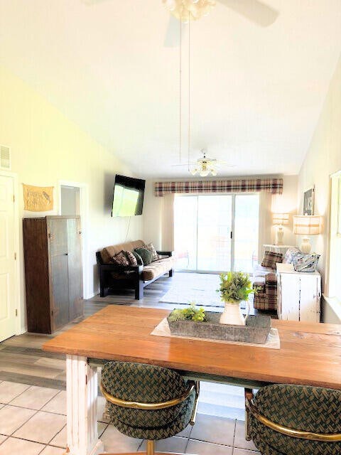 dining area with light hardwood / wood-style floors, high vaulted ceiling, and ceiling fan