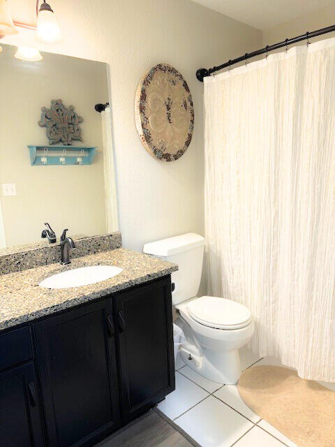 bathroom featuring walk in shower, vanity, toilet, and tile patterned floors