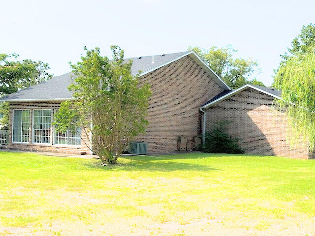 back of house featuring a lawn and central air condition unit