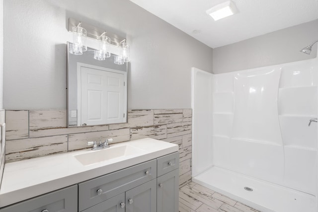 bathroom with vanity, walk in shower, and tile walls