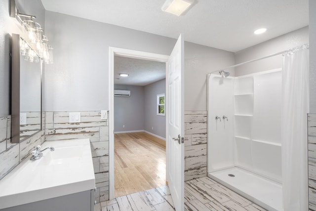 bathroom with a textured ceiling, a shower with shower curtain, a wall mounted air conditioner, and vanity