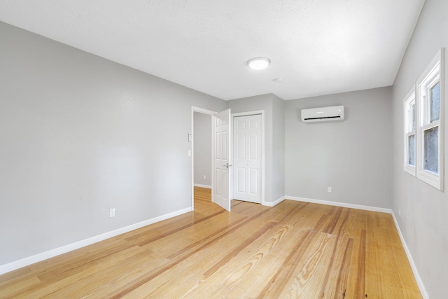 unfurnished room featuring wood-type flooring and a wall mounted air conditioner