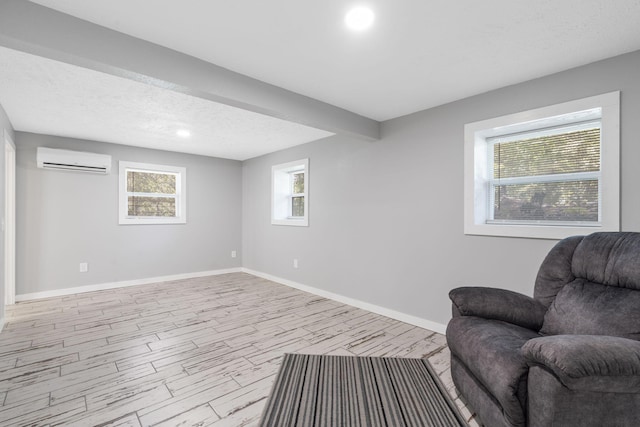 living area featuring a textured ceiling, light wood-type flooring, and an AC wall unit