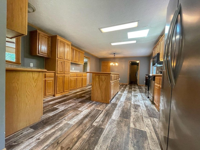 kitchen featuring a center island, brown cabinetry, black microwave, dark wood finished floors, and freestanding refrigerator