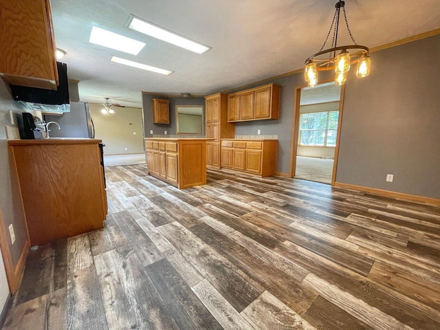 kitchen with dark hardwood / wood-style floors, stainless steel fridge, ceiling fan with notable chandelier, crown molding, and decorative light fixtures