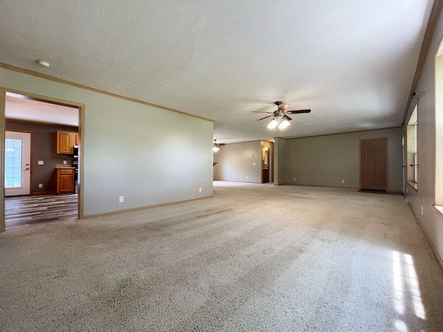 unfurnished living room featuring light carpet, ceiling fan, ornamental molding, and a textured ceiling