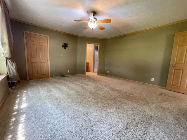empty room featuring a ceiling fan, a textured ceiling, light carpet, baseboards, and ornamental molding