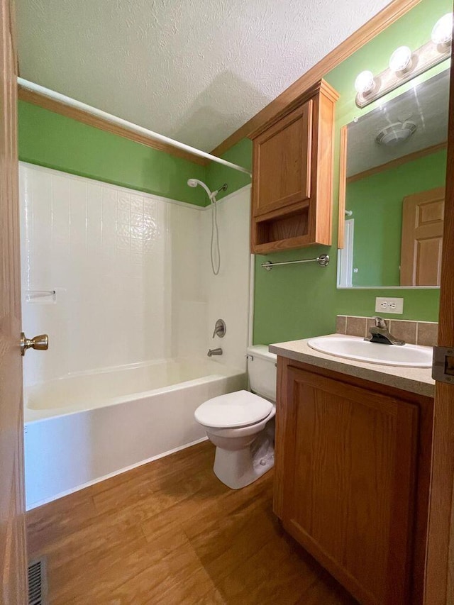 full bathroom featuring vanity, wood-type flooring, a textured ceiling,  shower combination, and toilet