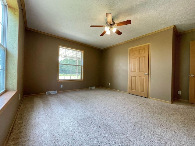unfurnished room with carpet, a ceiling fan, crown molding, baseboards, and a textured ceiling