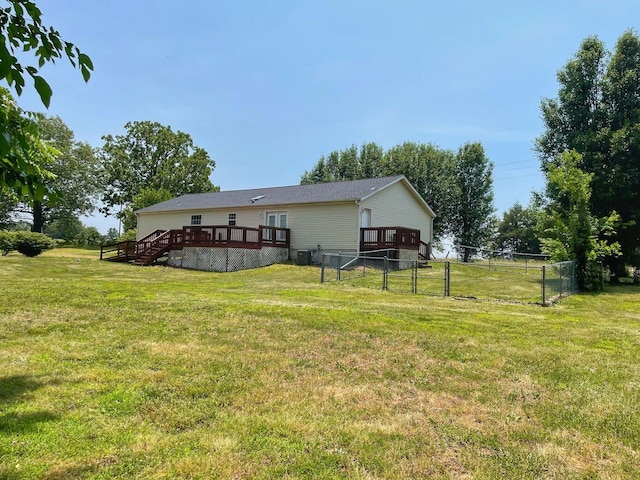 rear view of house featuring a yard, fence, and a deck