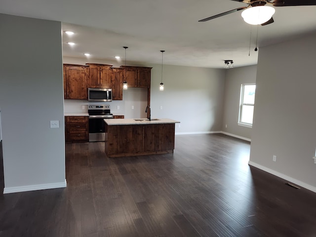 kitchen with sink, an island with sink, dark hardwood / wood-style floors, and appliances with stainless steel finishes