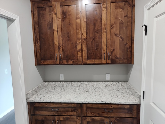 kitchen with light stone countertops and dark brown cabinetry