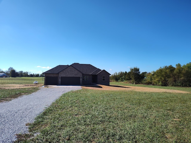 view of front of home featuring a front lawn, a rural view, and a garage