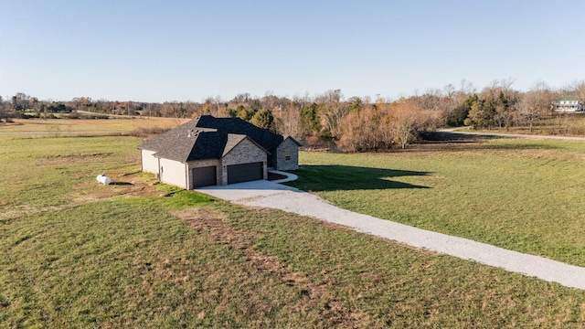 view of front of property with a rural view, a garage, and a front lawn