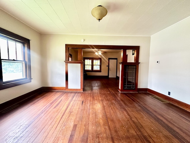unfurnished living room with wood-type flooring, baseboards, ceiling fan, and visible vents