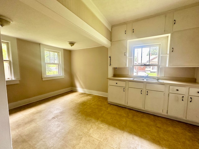 kitchen with a textured ceiling, sink, and white cabinetry