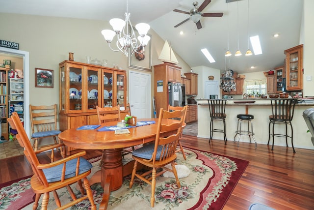 dining room with a skylight, ceiling fan with notable chandelier, sink, high vaulted ceiling, and dark hardwood / wood-style floors