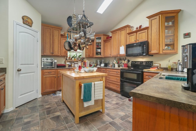 kitchen with black appliances, wood counters, a center island, and vaulted ceiling