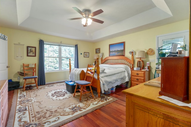 bedroom featuring hardwood / wood-style flooring, ceiling fan, and a tray ceiling