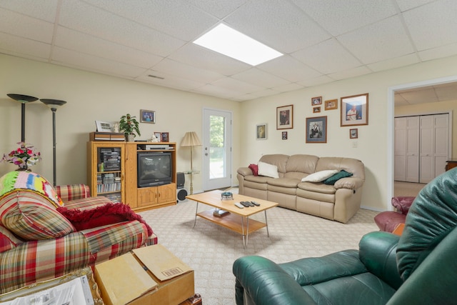 carpeted living room featuring a drop ceiling