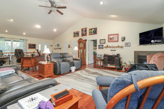 living room featuring lofted ceiling, ceiling fan, wood-type flooring, and a fireplace