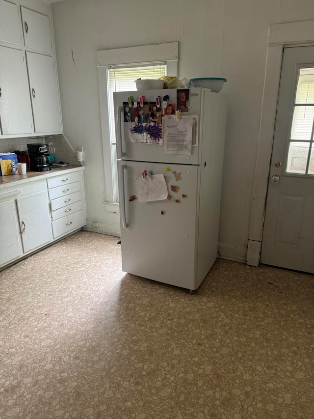 kitchen with white cabinets, white refrigerator, and decorative backsplash