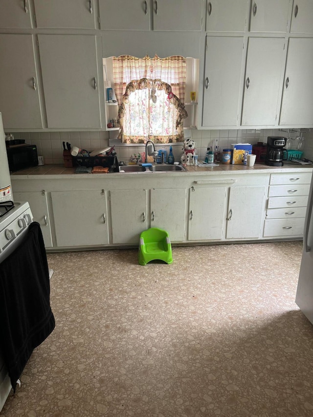 kitchen featuring white cabinets, sink, and tasteful backsplash