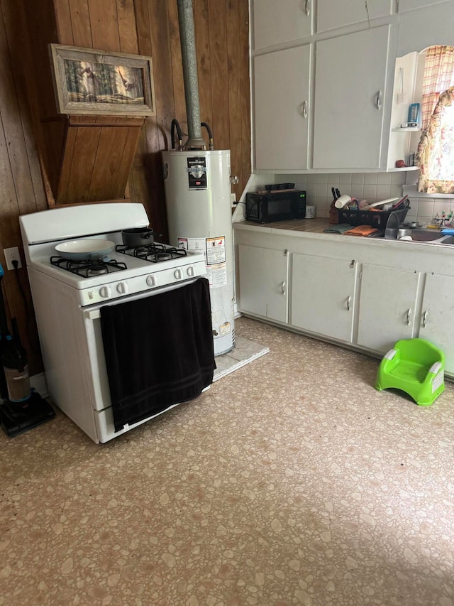 kitchen featuring water heater, wooden walls, decorative backsplash, white cabinets, and white range with gas cooktop