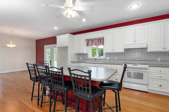 kitchen with white range with electric cooktop, a kitchen breakfast bar, light wood-type flooring, and white cabinets