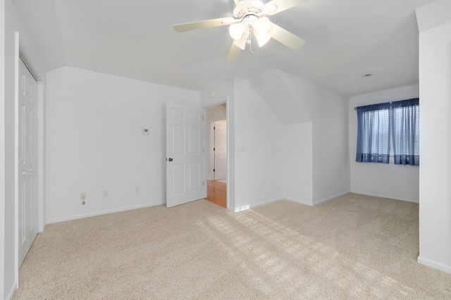 interior space with light carpet, a closet, vaulted ceiling, and ceiling fan