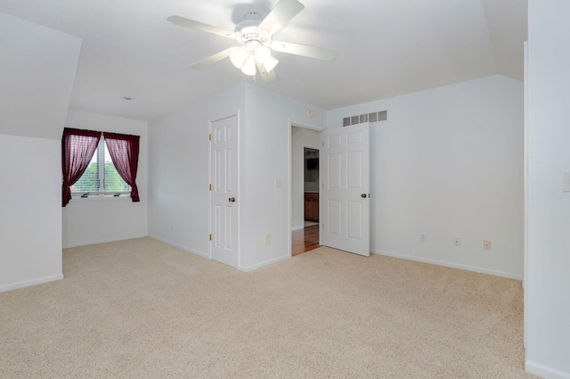 carpeted spare room with ceiling fan and vaulted ceiling