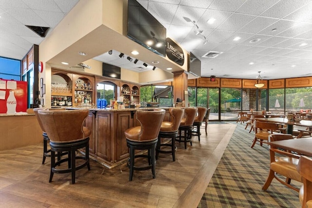 bar with hanging light fixtures and a wealth of natural light