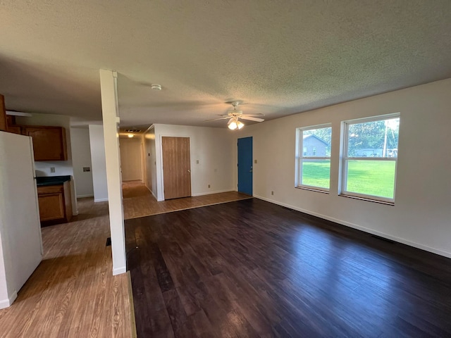 unfurnished living room with dark wood-type flooring, a textured ceiling, and ceiling fan