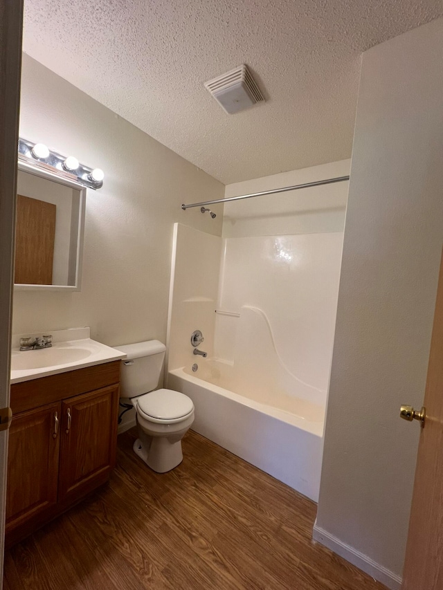 full bathroom with toilet, shower / bathing tub combination, hardwood / wood-style flooring, vanity, and a textured ceiling