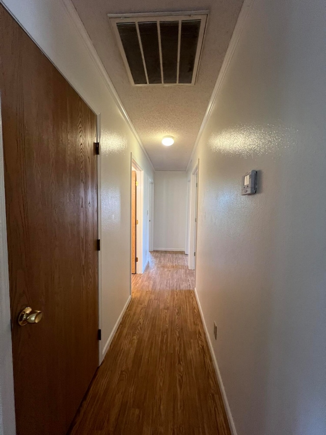 corridor with crown molding, hardwood / wood-style floors, and a textured ceiling