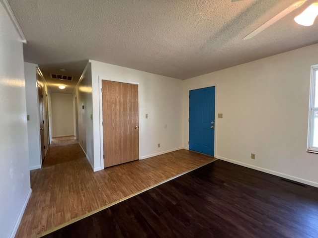 unfurnished room with a textured ceiling and dark hardwood / wood-style flooring