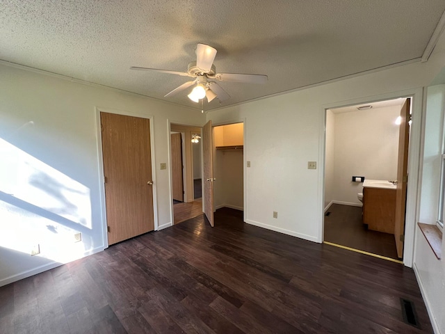 unfurnished bedroom featuring ensuite bathroom, ceiling fan, dark wood-type flooring, and a textured ceiling