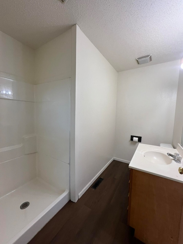 bathroom featuring walk in shower, vanity, hardwood / wood-style floors, and a textured ceiling