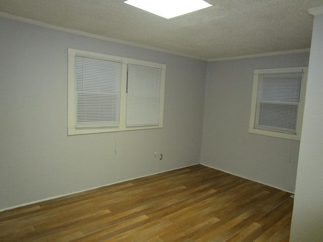 unfurnished room featuring hardwood / wood-style floors, ornamental molding, and a textured ceiling