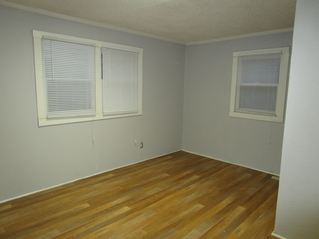 empty room featuring wood-type flooring, a textured ceiling, and ornamental molding