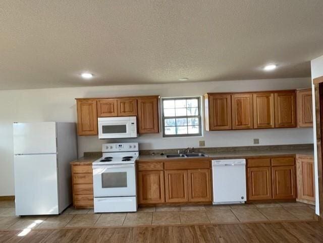 kitchen featuring white appliances, light hardwood / wood-style flooring, a textured ceiling, and sink