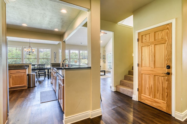 kitchen featuring ceiling fan with notable chandelier, pendant lighting, sink, and dark hardwood / wood-style floors