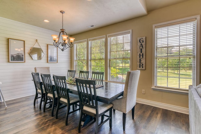 dining room featuring wooden walls, an inviting chandelier, and dark hardwood / wood-style flooring