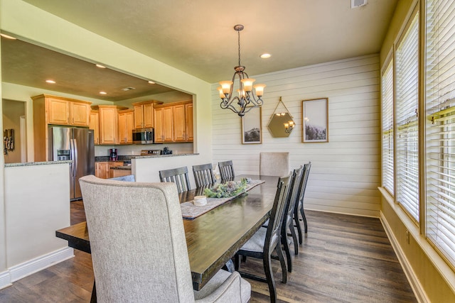 dining area with an inviting chandelier, wooden walls, and dark wood-type flooring