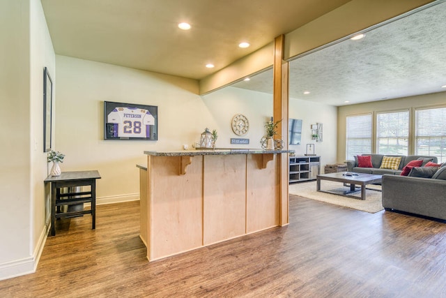 kitchen featuring light brown cabinets, kitchen peninsula, wood-type flooring, a textured ceiling, and a kitchen breakfast bar