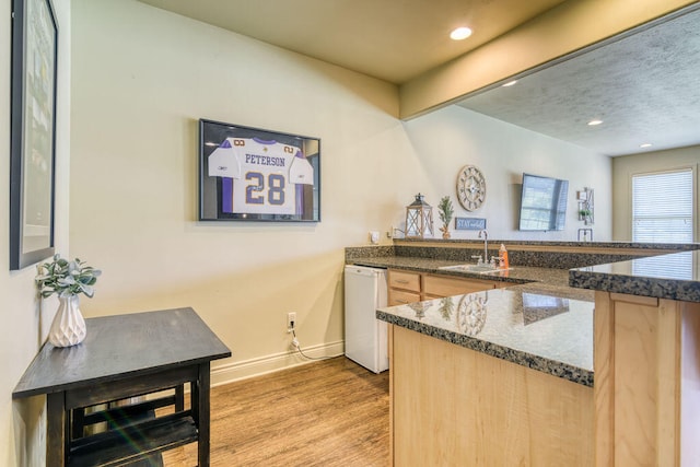 kitchen featuring light brown cabinets, hardwood / wood-style flooring, sink, and kitchen peninsula