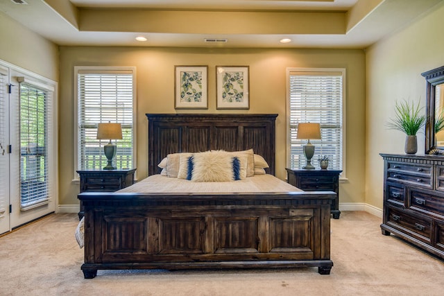 bedroom with access to outside, a tray ceiling, and light carpet